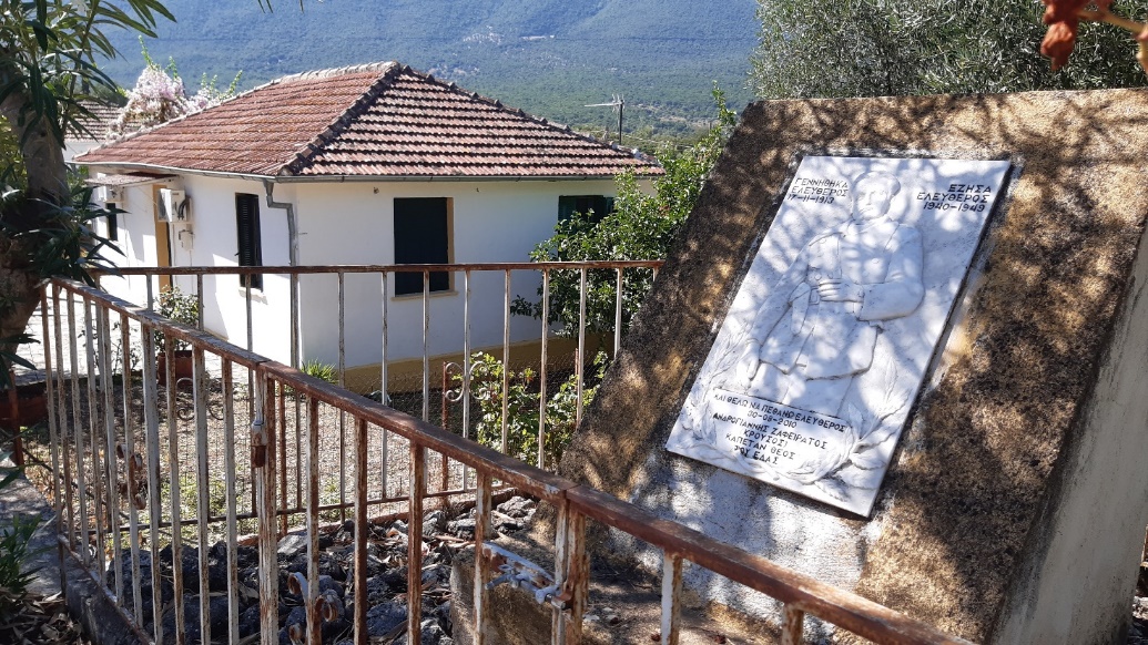 Mountain village. A marble relief with an ELAS fighter, at the edge of a courtyard. 