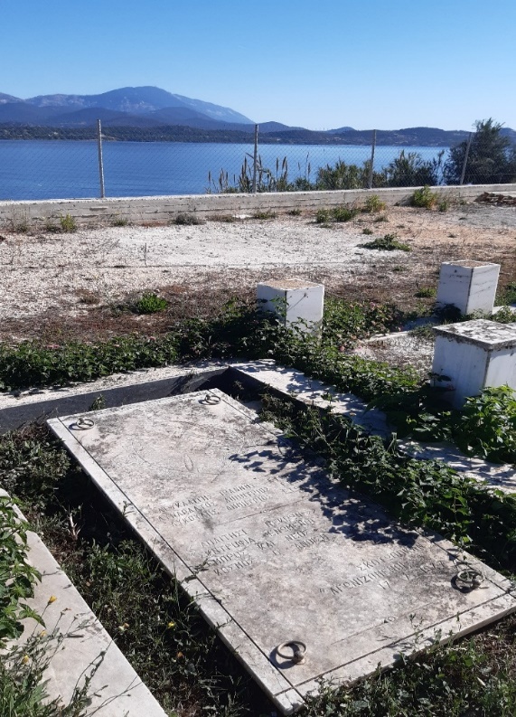 Tomb with a marble slab bearing a hammer and sickle. In the background, the sea.